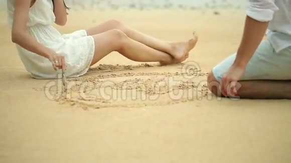 浪漫的年轻夫妇在沙滩上画心形视频的预览图