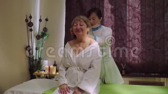 年轻的中国医生在给一位年长的女士按摩视频的预览图