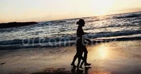 日落时分妈妈和小女儿在海滩上玩耍视频的预览图