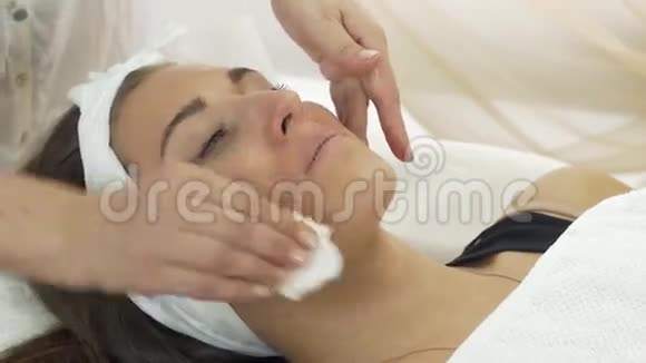 专业美容师用餐巾纸在美容院擦拭女孩的嘴唇视频的预览图