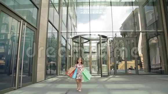 可爱的小女孩带着购物袋走出商店视频的预览图
