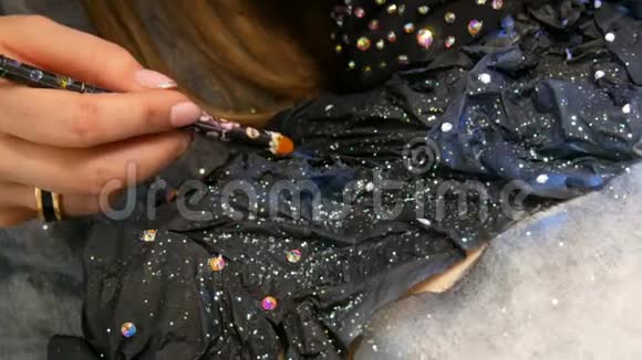 时尚设计师用闪闪发光的莱茵石闪闪发光的金属制成一个戴着黑色面具的模特外星人女孩的形象视频的预览图