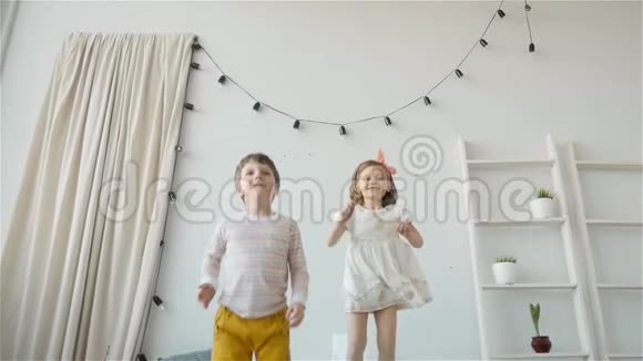 孩子们在床上蹦蹦跳跳的肖像小男孩和小女孩的兄妹玩得开心笑得开心视频的预览图