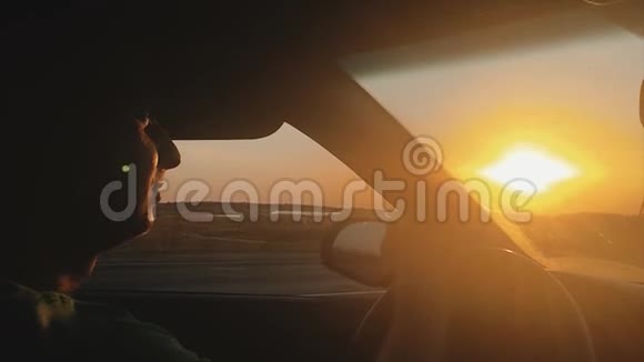 人类骑在一个自动美丽的阳光剪影日落慢动作视频开车旅行生活方式视频的预览图