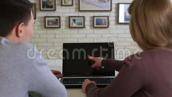 年轻夫妇坐在桌子旁看着笔记本电脑屏幕视频的预览图