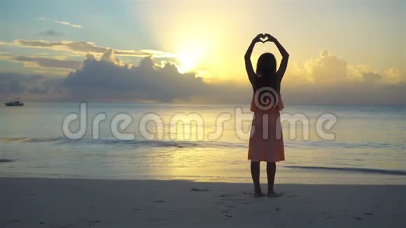 可爱快乐的小女孩在日落时在白色海滩上玩得很开心视频的预览图