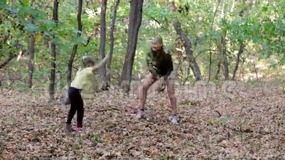 母亲和女儿在秋天公园里扔树叶视频的预览图