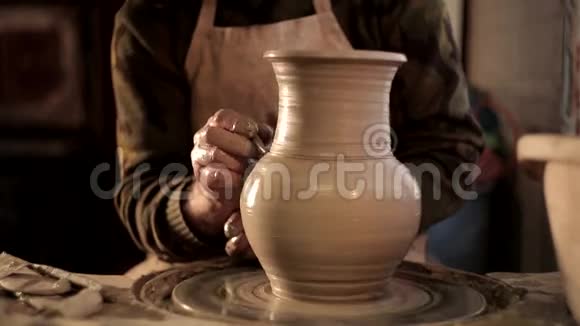在传统陶器上用錾子将陶工的手设计图案与桌上模糊的其他设备粘土结合起来视频的预览图