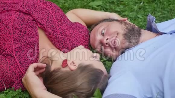 幸福的一对夫妇在绿草上的公园里休息动作缓慢微笑的男人和女人交谈享受温暖的夏日视频的预览图
