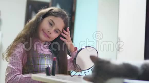 小女孩梳她的室内头发做发型少女撅起她的梳子和镜子视频的预览图