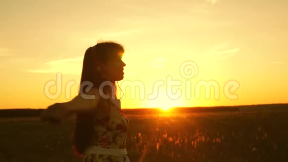 美丽的女孩戴着耳机和智能手机在温暖的夕阳下飞行快乐的女孩视频的预览图
