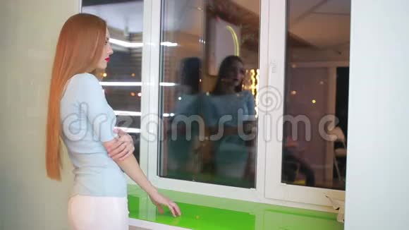 女人站在窗台旁望着窗外夜城视频的预览图