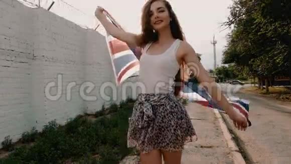 微笑的少女用大彩旗在风中编织复古的色彩拍摄站在墙边的年轻女子视频的预览图