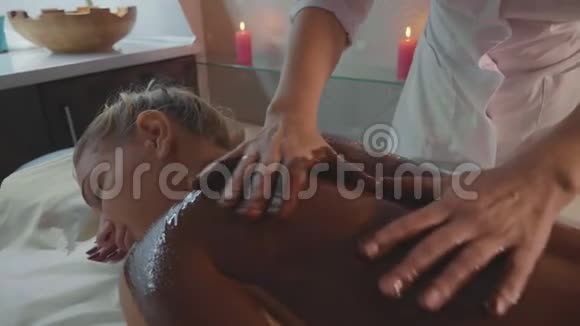 美容师用巧克力为年轻美女按摩水疗沙龙视频的预览图