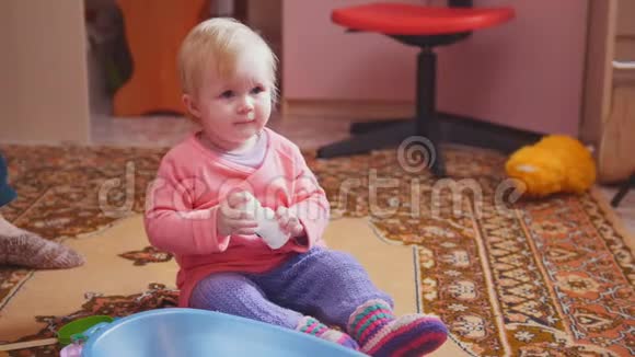 可爱的小女孩在玩她的玩具坐在地板上视频的预览图