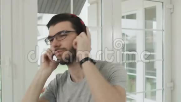 戴眼镜的开朗男人用耳机听音乐视频的预览图
