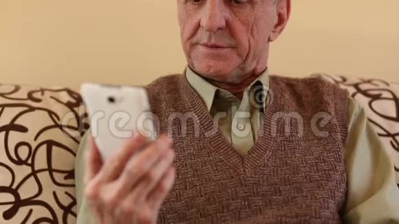一个年长的男人在她的智能手机里翻来覆去地看照片视频的预览图