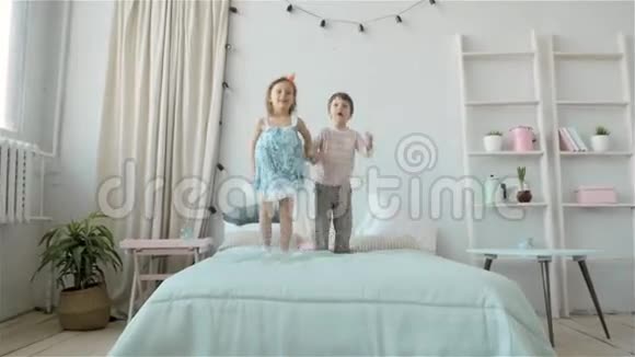 孩子们在床上蹦蹦跳跳的肖像小男孩和小女孩的兄妹玩得开心笑得开心视频的预览图