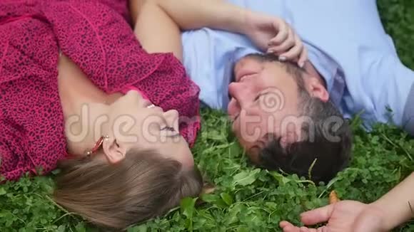 幸福的一对夫妇在绿草上的公园里休息动作缓慢微笑的男人和女人交谈享受温暖的夏日视频的预览图