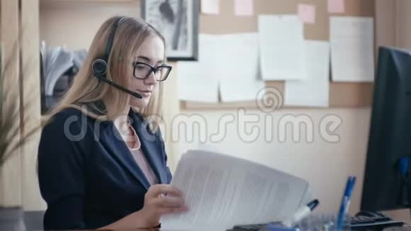 呼叫中心员工在办公室工作一个金发女孩戴着眼镜坐在办公室的桌子旁视频的预览图