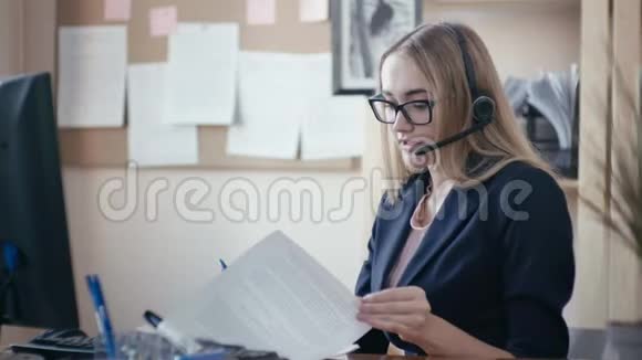 呼叫中心员工在办公室工作一个金发女孩戴着眼镜坐在办公室的桌子旁视频的预览图