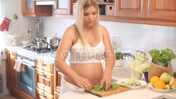 孕妇把生菜切在厨房的木板上视频的预览图