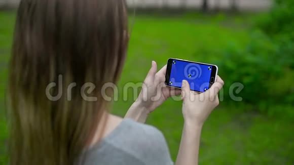女孩在绿色屏幕上用记号笔触摸智能手机视频的预览图