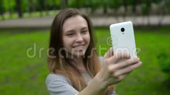 一位美丽的年轻女子的肖像在街上自拍一部智能手机视频的预览图