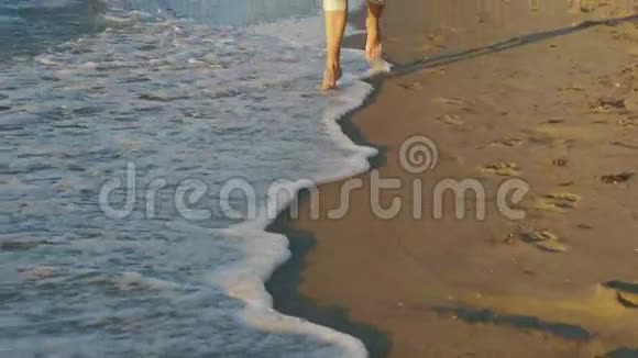 靠近沿着海滩海岸线奔跑的人的双腿慢动作视频的预览图
