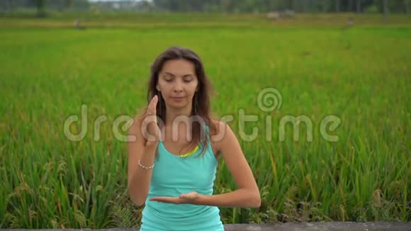 一位年轻女子用巴厘岛的方式为穆拉哈拉查克拉做冥想的慢动作稳定镜头视频的预览图