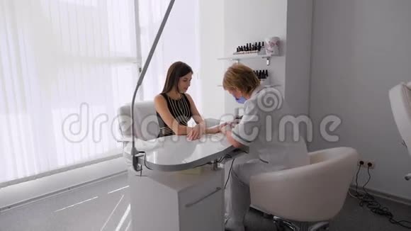 美甲沙龙里的女人接受美容师的美甲女人正在修指甲视频的预览图
