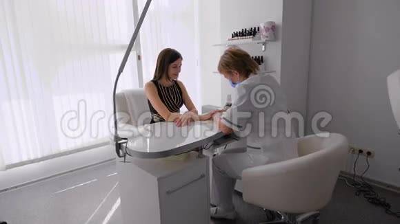 美甲沙龙里的女人接受美容师的美甲女人正在修指甲视频的预览图