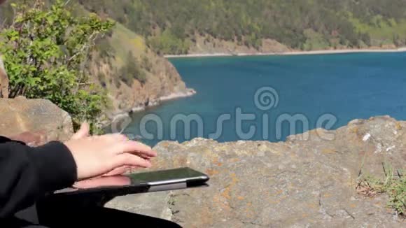 女孩坐在贝加尔湖岸边的岩石上用一块石碑视频的预览图