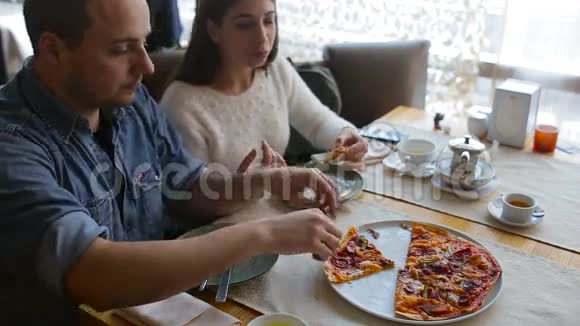 在城里的咖啡馆里聊天和吃披萨的夫妇视频的预览图