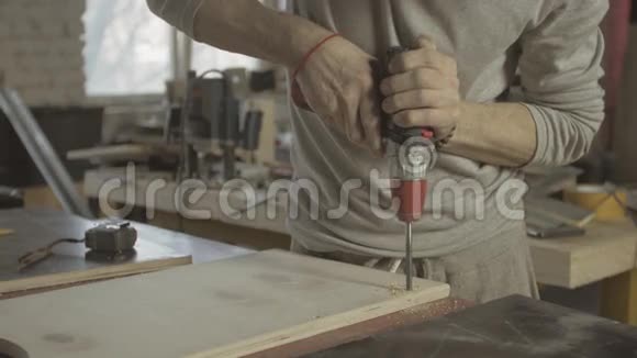 专业的老木匠用钻头在抛光的木板上打洞性感视频的预览图