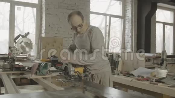 木工将圆锯固定在工作台的木板边缘视频的预览图