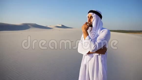 庄严的阿拉伯阿联酋酋长国人看着很难进入距离和思考站在广阔的沙漠中的夏天视频的预览图