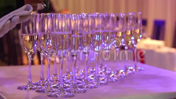 服务员把香槟倒入玻璃杯中香槟杯放在自助餐桌上餐厅或酒店的大厅视频的预览图