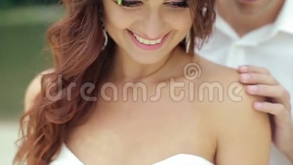 新郎抚摸新娘的肩膀微笑着向下看视频的预览图