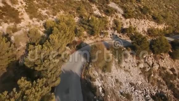 孤独的旅行者骑着摩托车在壮丽的山路上的无人机镜头视频的预览图