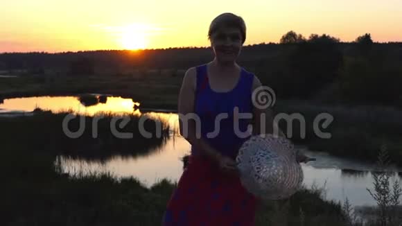 快乐的女人在日落时戴着草帽跳舞视频的预览图