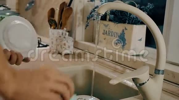 男人正在厨房里用肥皂洗盘子带有侧面摄像机运动的特写镜头视频的预览图