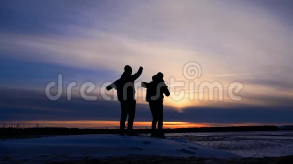 两个人背着背包和其他装备站在山顶上的轮廓表达了能量和幸福视频的预览图