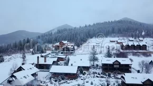 冬季山区有人居住地区的空中活动雪山山坡上的村庄建筑和房屋视频的预览图
