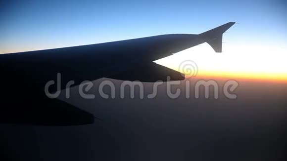 日出时在云层上方飞行的大飞机机翼视频的预览图