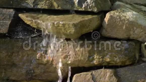 花园的石头瀑布水流过石头朝阳照瀑布视频的预览图