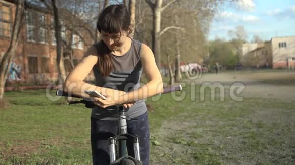 年轻女子拿着自行车用手机视频的预览图
