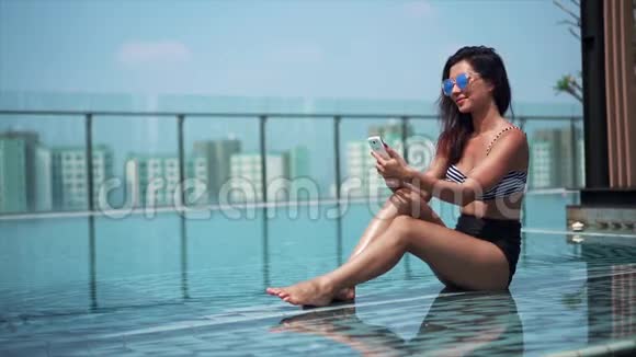 快乐的女人在泳池边用手机视频的预览图