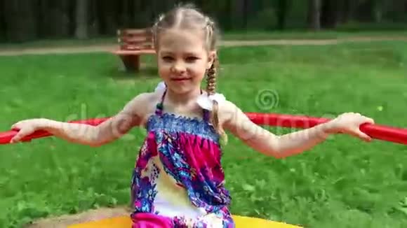 快乐的小可爱女孩在夏天的绿色公园里骑着环形交叉路口视频的预览图