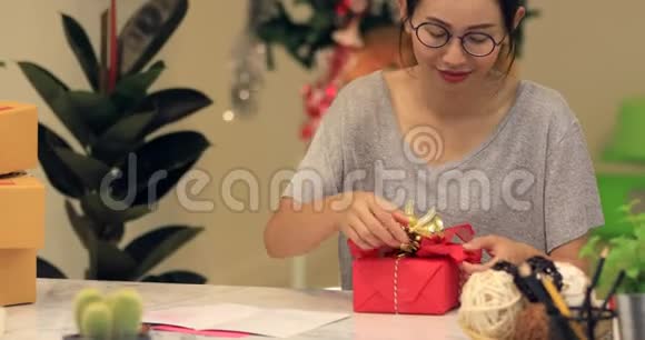 女人用纸包裹圣诞节或其他节日手工礼物视频的预览图